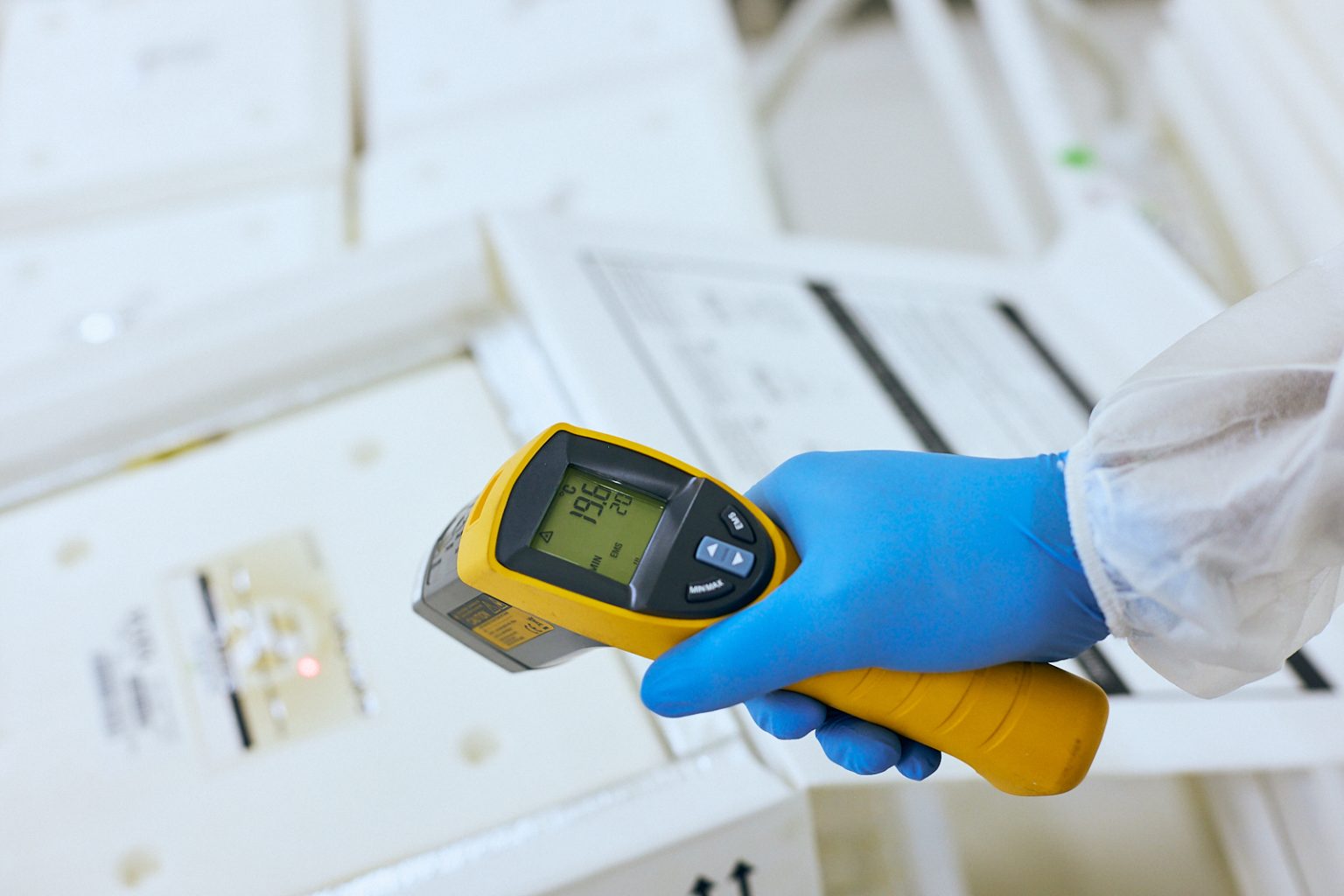 Technician using an infrared temperature scanner on a shipping box