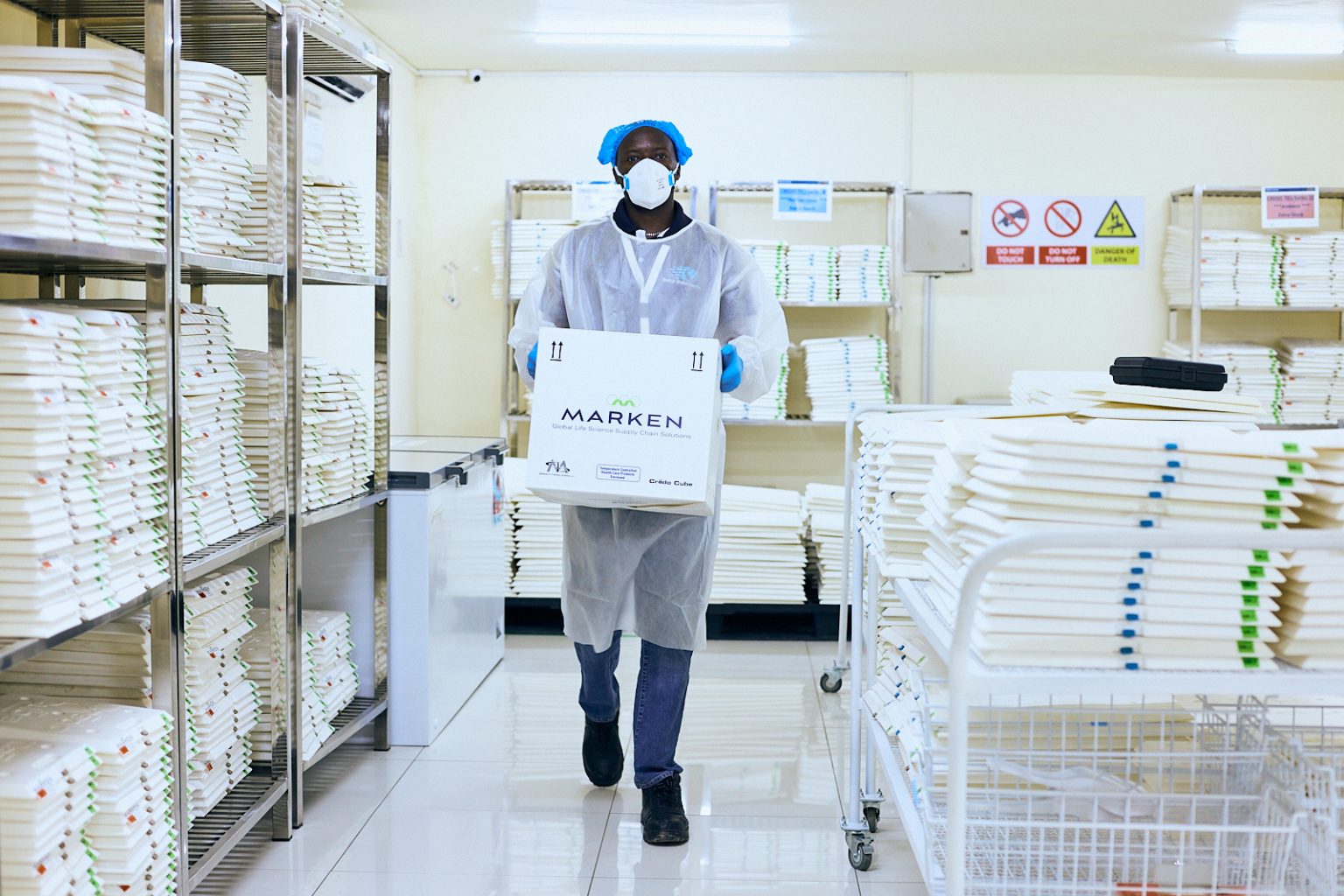 Technician carrying a Marken branded box through the warehouse